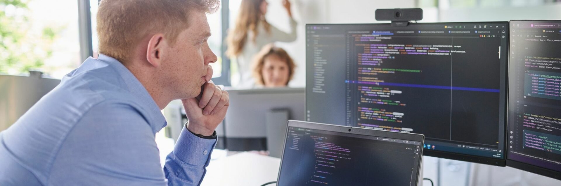 A man sits focused in front of a computer displaying complex lines of code. The scene conveys a sense of technical expertise and innovative problem-solving as he interacts with the information on the screen. This image symbolizes the use of technologies like Retrieval Augmented Generation (RAG) for efficient data processing.