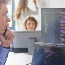 A man sits focused in front of a computer displaying complex lines of code. The scene conveys a sense of technical expertise and innovative problem-solving as he interacts with the information on the screen. This image symbolizes the use of technologies like Retrieval Augmented Generation (RAG) for efficient data processing.