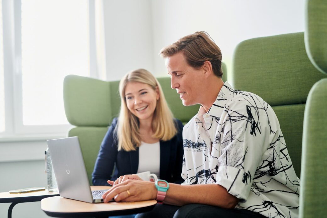 Two People sitting there and watching on a Laptop