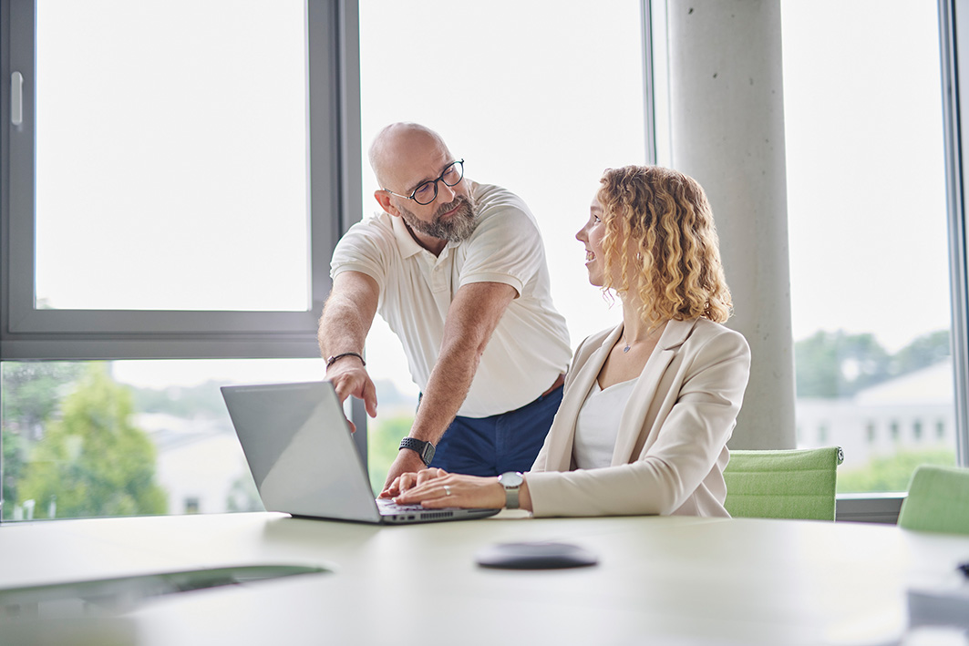 Two employees looking for their electronic signature software from germany on laptop